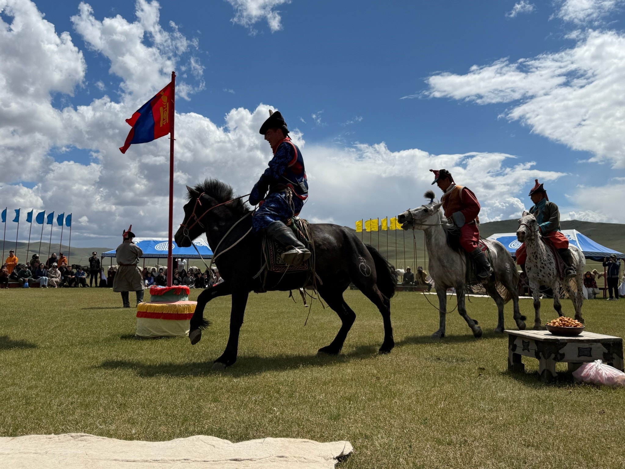 Horseback riders carrying the Mongolian flag at the Naadam festival