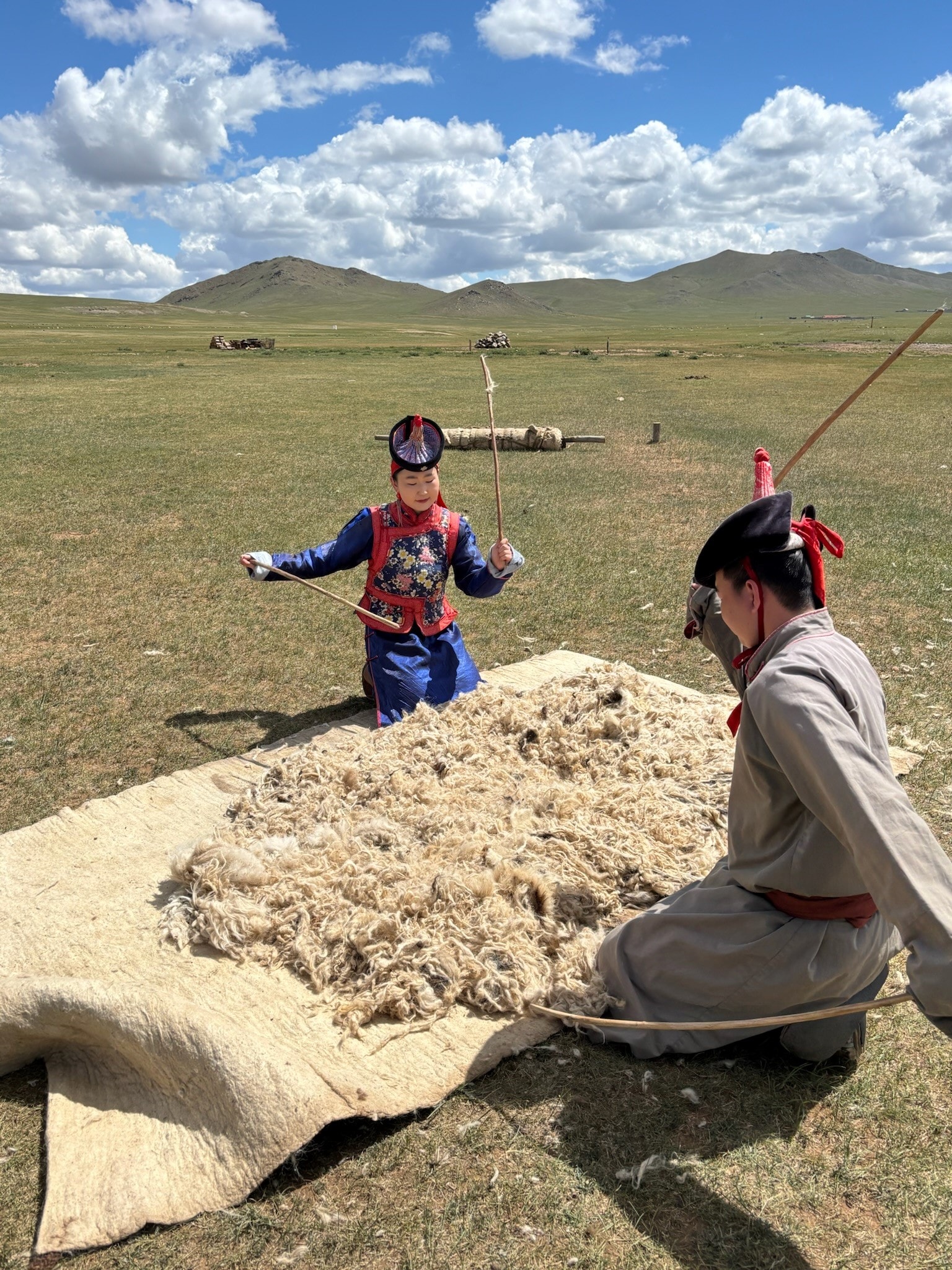 Two people in traditional dress processing wool on the Mongolian steppe